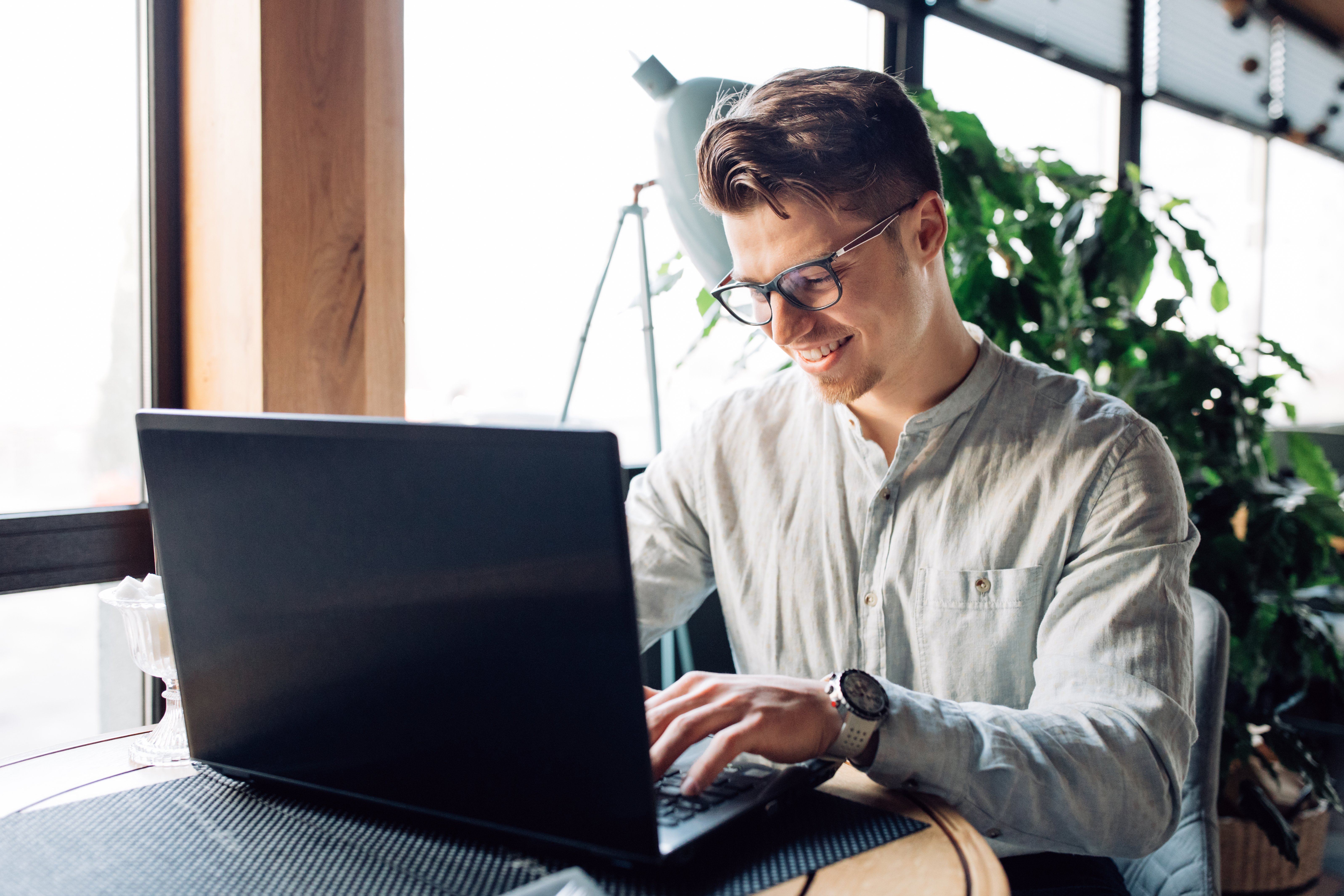 attractive-businessman-eyeglasses-working-laptop-typing-spending-time-cafe